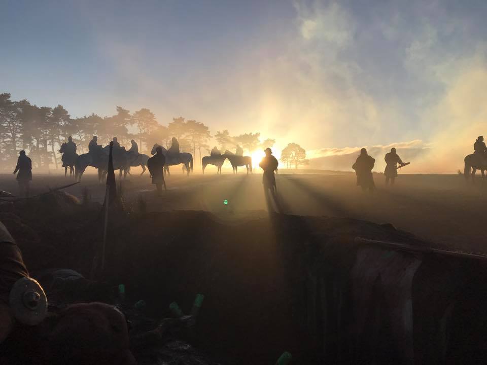 Cast, crew and horses on a film set at sunrise
